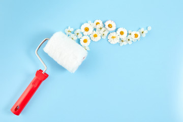 Obraz premium Creative spring blossom concept. Paint roller with flower on a blue pastel background. Spring time. Space for text.