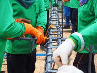 workers hands using steel wire and pincers to secure rebar before concrete is poured over it.
