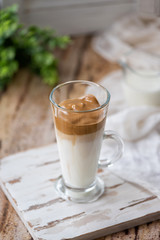 Dalgona coffee with ice and fluffy creamy whipped instant coffee on wooden tray. Trend korean drink latte on marble brown table