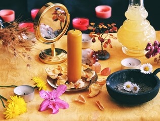 Yellow candle on Litha midsummer Sabbat Solstice celebration witch altar filled with flowers, rose petals, dandelions, crystals, golden mirror and other random things corresponding to the Sun - obrazy, fototapety, plakaty