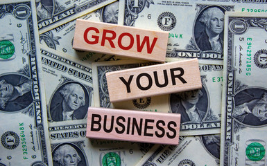 Concept text 'grow your business' on wooden blocks on a beautiful background from dollar bills.