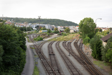 Fototapeta na wymiar Desolated railway station and transshipment point. Railroad track is overgrown with grass - termination and end of the rail. City and town or Prague - Smichov in the distance.