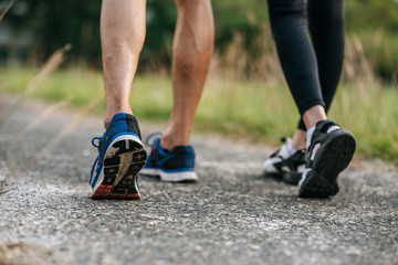 Runner woman and man feet running on road closeup on shoe. Sports healthy lifestyle concept.