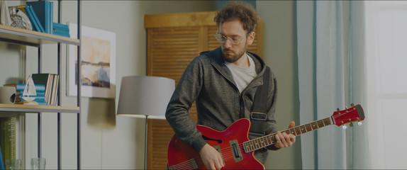 DX MED Caucasian male playing his electric guitar at home, practicing during quarantine