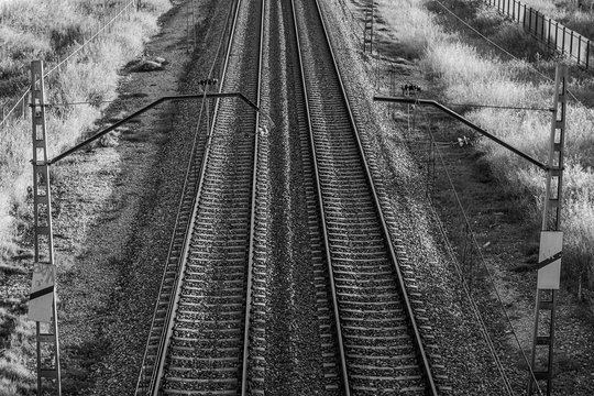 Detail of parallel train tracks at sunset. Black and white.