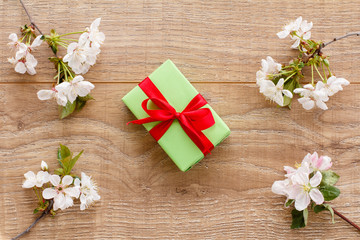 Gift box with cherry flowers on the wooden background.