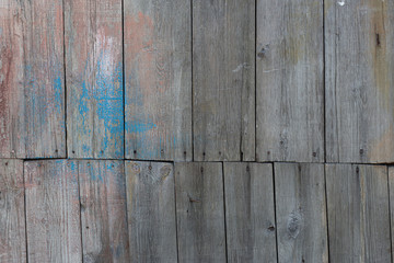 old wall of wooden boards with nails and peeling colorful paint
