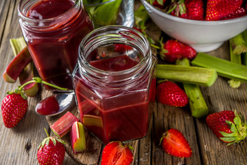 Homemade strawberry rhubarb jam or sauce, with fresh rhubarb and strawberries and spices, wooden rustic background copy space