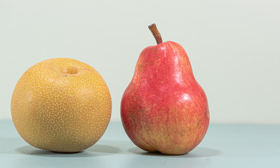 Fresh fruits of Asian pear (Pyrus pyrifolia) and Red pear (Pyrus communis 'Williams') on blue background