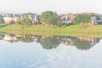 Fototapeta na wymiar Two-story bungalow houses reflection on idyllic lake at suburban neighborhood near Dallas, Texas, USA