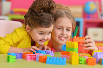 Two little girls playing with colorful plastic blocks