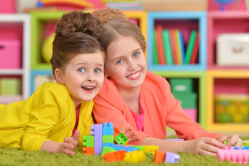 Two little girls playing with colorful plastic blocks