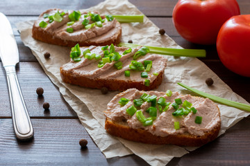 Fototapeta na wymiar Sandwich with pate with green onion on a wooden background. Sandwich on crumpled paper with herbs.