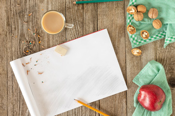 Open sketchbook, pencil, red Apple on a checkered napkin with walnuts. The view from the top.