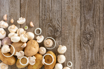 Fototapeta na wymiar Mushrooms, potatoes and onion rings with garlic on a wooden background. Template for text, top view.