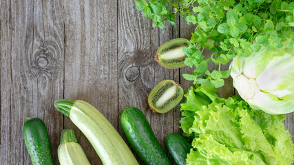 Assorted green vegetables on a wooden background. Template for text, top view.