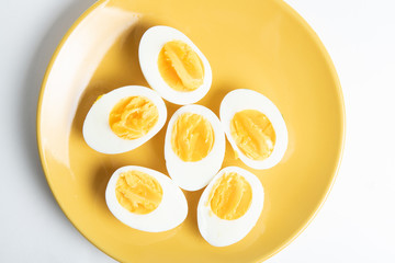 Bolied half-cut pieces of eggs on yellow plate