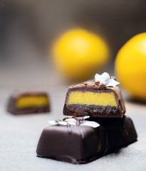Chocolate citrus candies without sugar and lemons on the background. Raw vegan chocolate candies. Lactose free candies. Gluten free candies. Without artificial dyes chocolate.