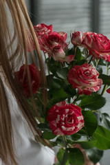 Bouquet of fresh flowers in woman's hand. Female hand holds flowers near the gray wall. Art decoration at the wedding. Florist. Image with selective color.