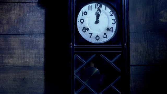 Close up of antique pendulum wall clock on midnight