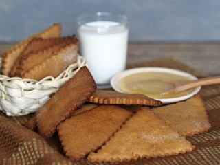 Home cooking.Diet cookies made from rye flour, a glass of milk on an ancient wooden table with a gray background.