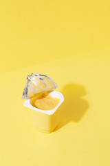 Banana and vanilla pudding or yogurt plastic cup on pastel yellow background.Minimal abstract food concept