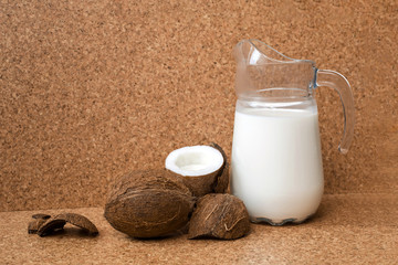 Top view of coconut milk in jug and coconut are on wooden background, cork background. Coconut...