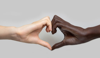 Black and white heart-shaped hands on a grey isolated background. The concept of inter-racial...