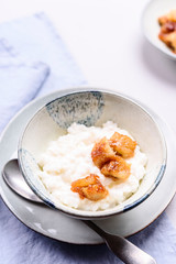 Creamy Rice Porridge or Pudding with caramelized bananas in bowl on grey concrete background. Selective focus
