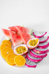 White plate of sliced fruit. Fresh fruits and vitamins. Still life colored summer fruits.