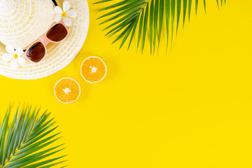 Summer background. Hat, sunglasses, palm leaves and fruits on yellow background. Travel or...