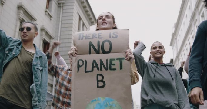 Group of protestors marching on the streets with signs and chanting. Activists protesting against pollution and global warming.
