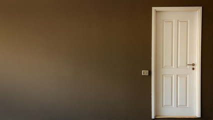 Light switch on the gray textured wall next to the white door with metallic handle