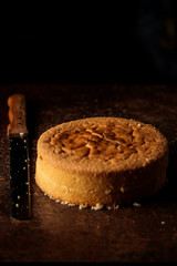 Homemade plain chiffon or sponge cake with a knife for bread on a dark background. Ideal sponge cake on wooden table blank space for text selective focus. cake making ingredient. dark copyspace.