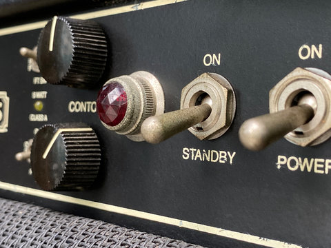 Close-up stanby switch vintage head power amplifier with black knob and control panel. clean and hi-gain distortion for rock to metal, Blues, and jazz genres. Music business concept.