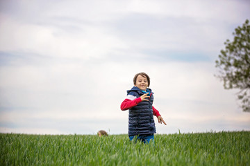 Fototapeta premium Preteen children, boys, running in green field on a cloudy day