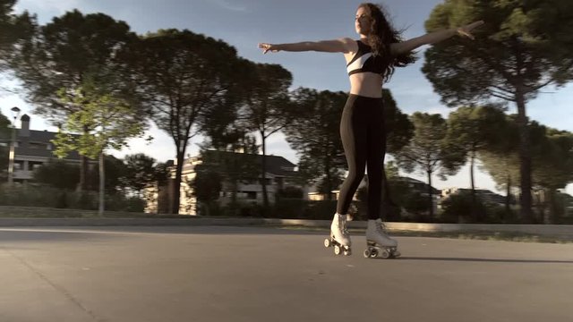 Pretty skater girl skating on roller skates at sunset