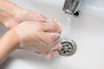 Fototapeta premium thorough hand washing with soap in the sink, self-disinfection, skin treatment with foam and water, antibacterial and antiviral use, close-up 