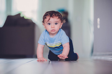 7 month old boy learning to crawl and crawling and playing on the wooden floor of his home hallway.  chasing his toys and learning new milestones 