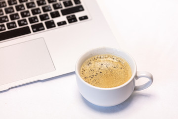 Cup of coffee and part of a computer on a white background