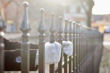 woman holds on to the bars of the fence.