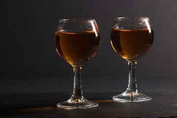 Glass of whiskey on a black stone slate board on black background. Side view, low key, close up.