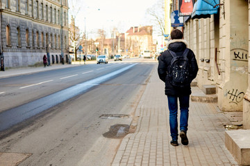 Fototapeta premium Riga, Latvia- February 07, 2020: a man with a backpack is walking along the street.