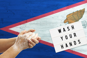 American Samoa flag background on wooden surface. Minimal wash your hands board with minimal...