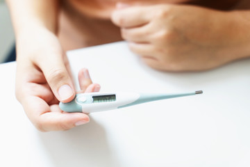 close up of woman checking thermometer and measure body temperature.
