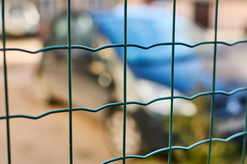 Car behind the fence net. Parking, fine area.