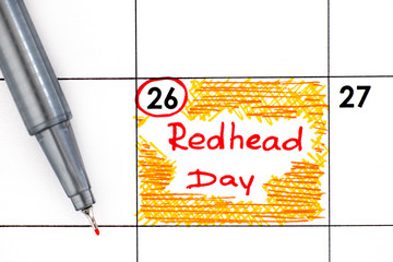 Reminder Redhead Day in calendar with pen.