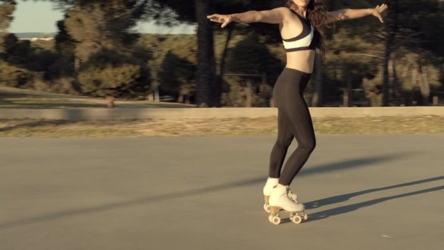 Pretty skater girl skating on roller skates at sunset