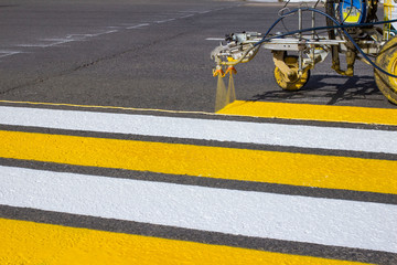 Road workers use hot-melt scribing machines to painting pedestrian crosswalk on asphalt road surface in the city. © Torkhov
