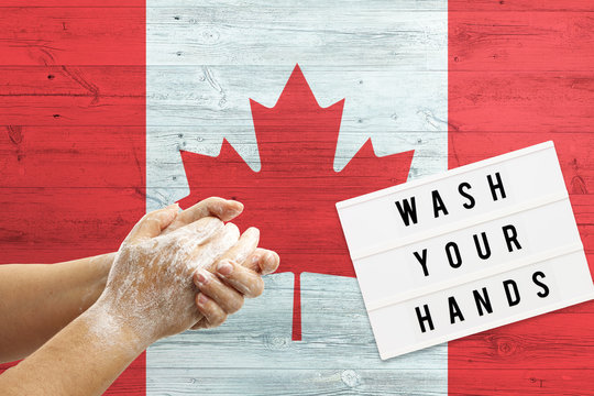 Canada Flag Background On Wooden Surface. Minimal Wash Your Hands Board With Minimal International Hygiene Concept Hand Detail.